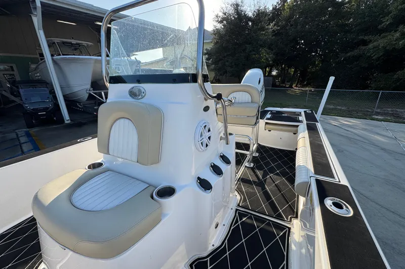 Slide: The Image of 2021 Sea Born FX24 Bay boat interior with seating and console, docked outdoors. - 23