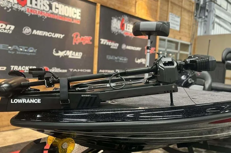 Slide: The Image of 2026 Triton 19 TrX Patriot boat with Lowrance Ghost trolling motor at a showroom. - 13