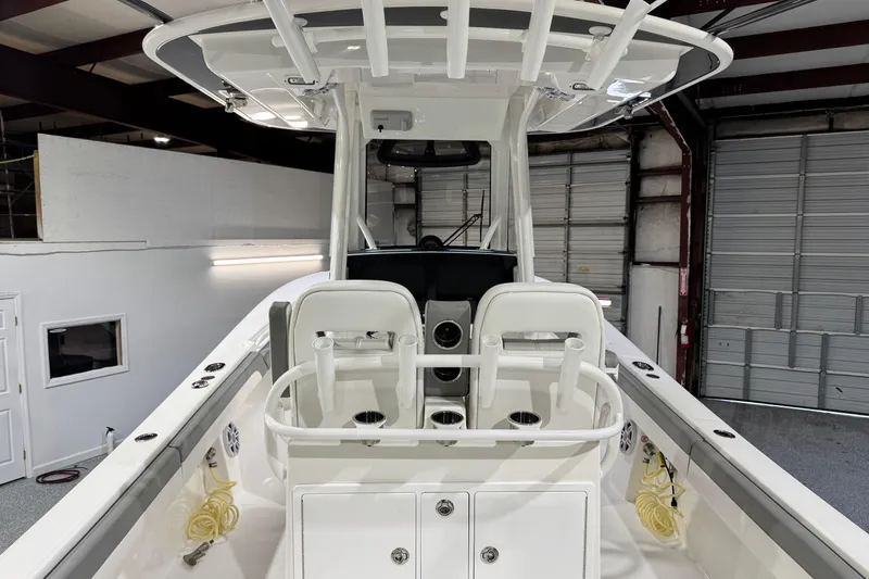 Slide: The Image of 2023 Regulator 28 boat interior with dual seats and rod holders in a garage setting. - 8
