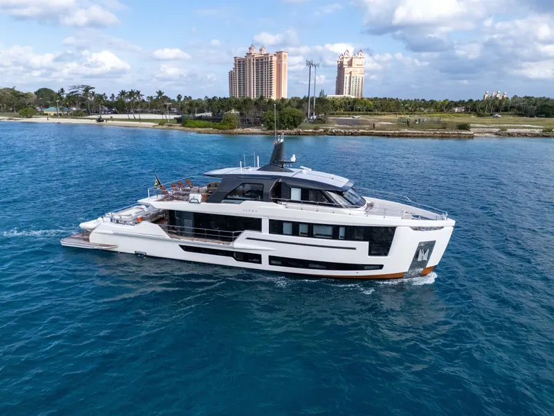 Slide: The Image of Luxurious 2025 Alpha Squalo Co Ownership yacht cruising in clear blue waters near a coastal cityscape. - 2