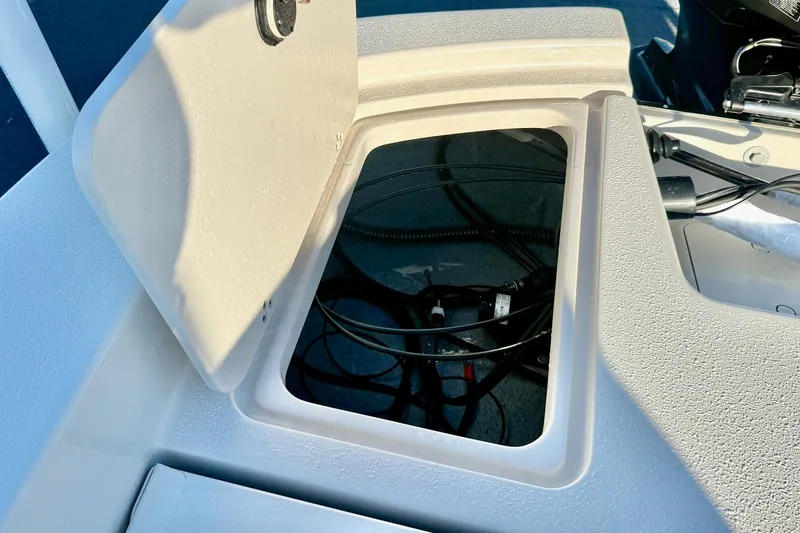 Slide: The Image of 2026 Carolina Skiff 24 Ultra Elite boat storage compartment with open hatch and visible wiring. - 37