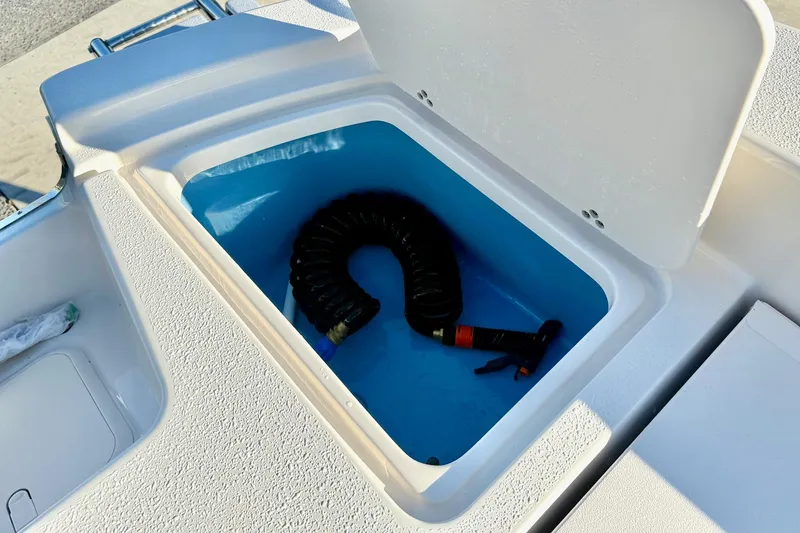 Slide: The Image of Storage compartment on 2026 Carolina Skiff 24 Ultra Elite boat with coiled hose. - 38