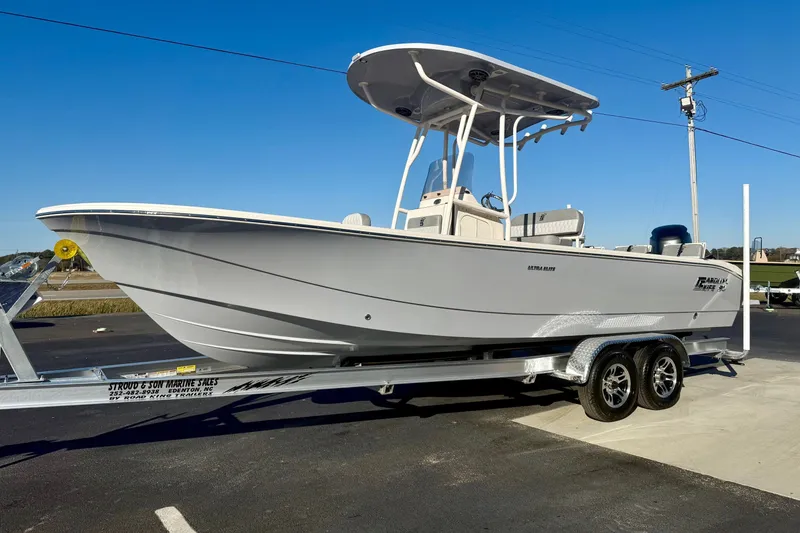 Slide: The Image of 2026 Carolina Skiff 24 Ultra Elite boat on trailer, parked outdoors under clear blue sky. - 6