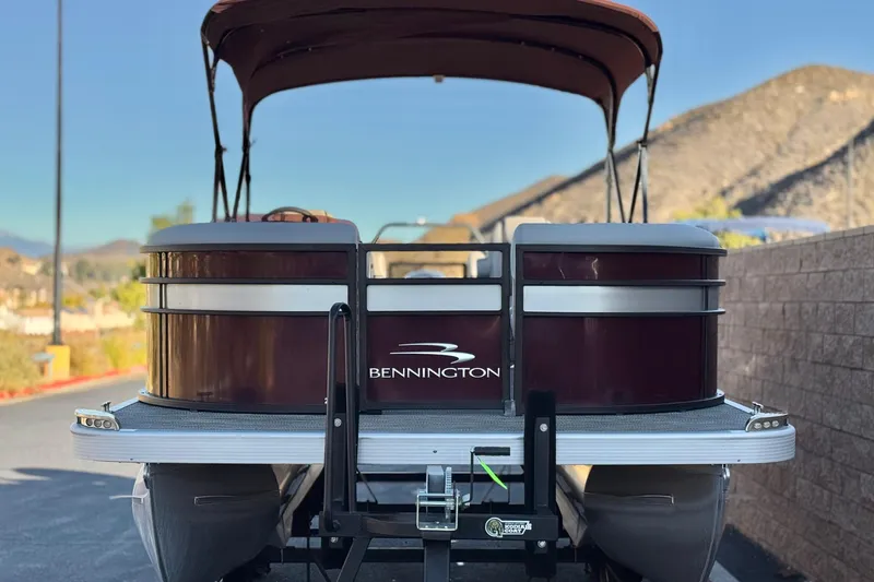 Slide: The Image of 2023 Bennington 22 XSR pontoon boat with canopy, parked on a trailer. - 2