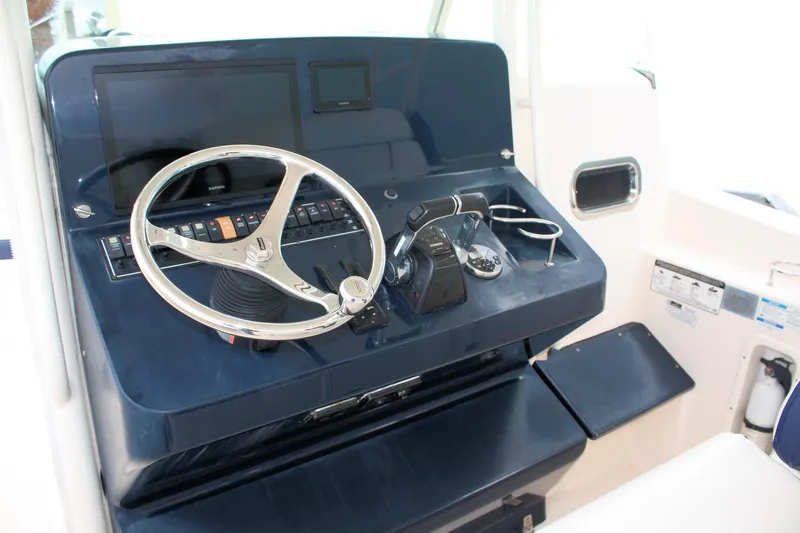 Slide: The Image of 2013 Pursuit ST 310 Sport boat helm with steering wheel and controls. - 19