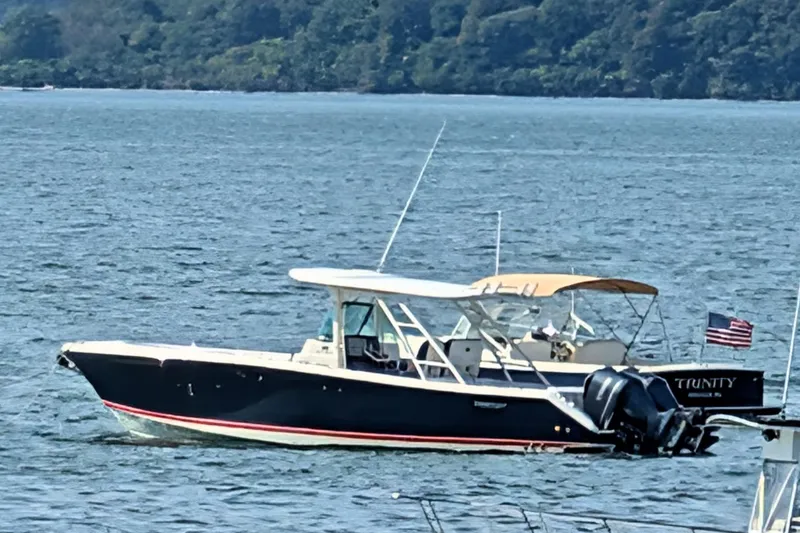 Slide: The Image of 2013 Pursuit ST 310 Sport boat on water, with American flag, scenic background. - 2