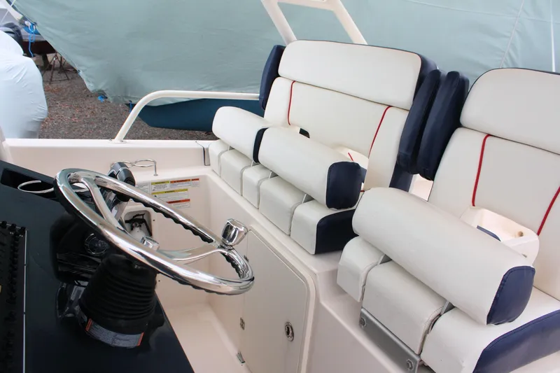 Slide: The Image of 2013 Pursuit ST 310 Sport boat interior with steering wheel and cushioned seating. - 24