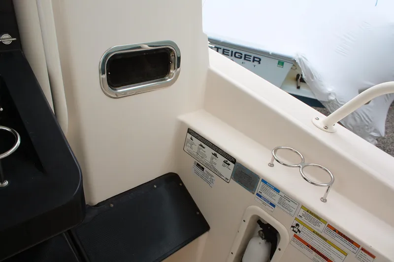Slide: The Image of Interior view of a 2013 Pursuit ST 310 Sport boat, featuring safety labels and cup holders. - 26