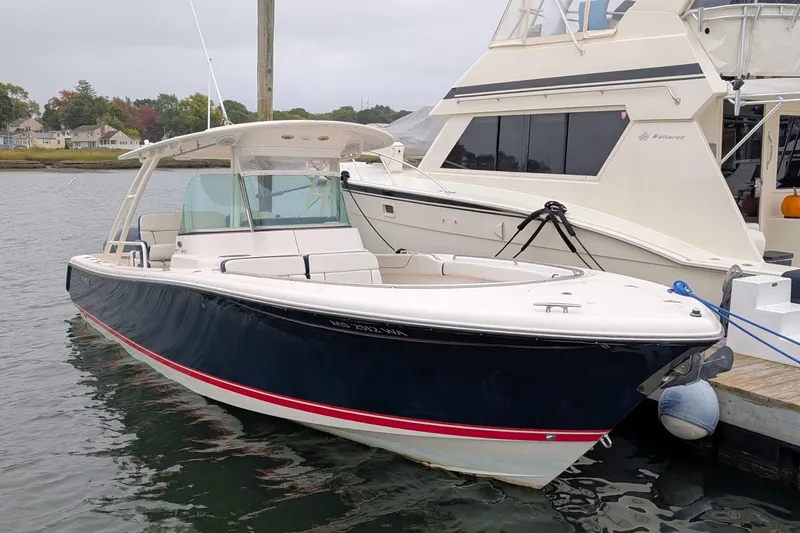 Slide: The Image of 2013 Pursuit ST 310 Sport boat docked in a marina, featuring sleek design and spacious deck. - 3