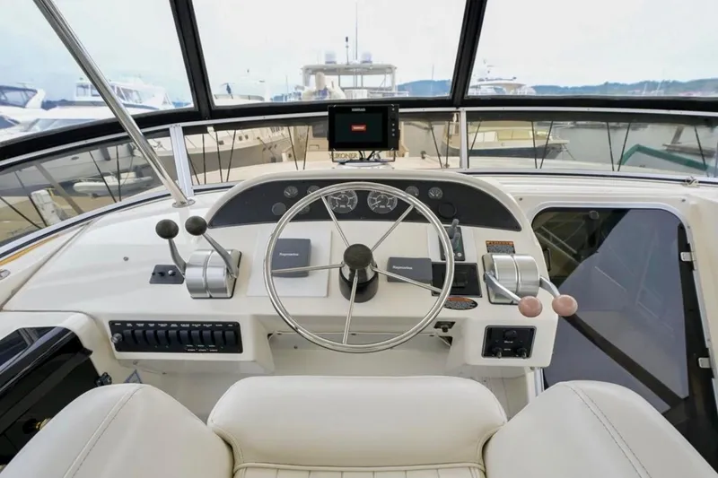 Slide: The Image of 2004 Meridian 490 Pilothouse interior with white seating and helm, docked at marina. - 11