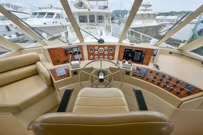 Slide: The Image of Luxurious 2004 Meridian 490 Pilothouse interior with helm, beige seating, and marina view. - 18
