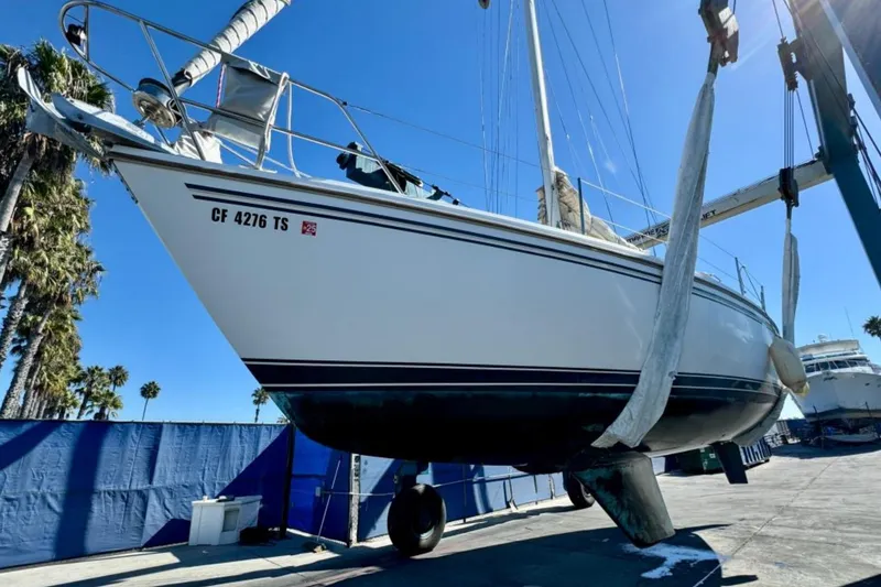 Slide: The Image of 1988 Catalina 36 sailboat in dry dock, suspended for maintenance under clear blue sky. - 23