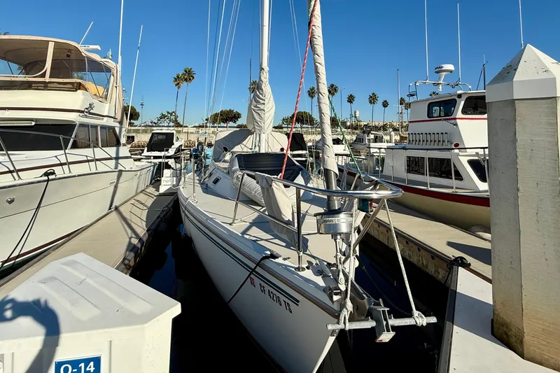 Slide: The Image of 1988 Catalina 36 sailboat docked at marina, surrounded by other boats, clear blue sky. - 3