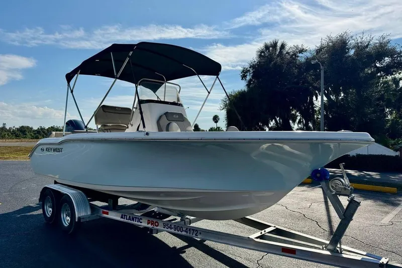 Slide: The Image of 2023 Key West 219 FS boat on trailer, parked outdoors under a clear sky. - 3