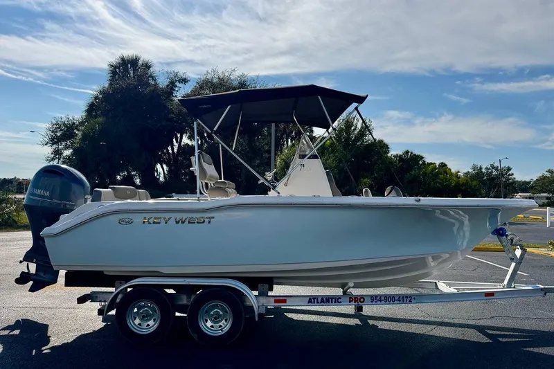 Slide: The Image of 2023 Key West 219 FS boat on trailer, parked outdoors under a clear sky. - 7