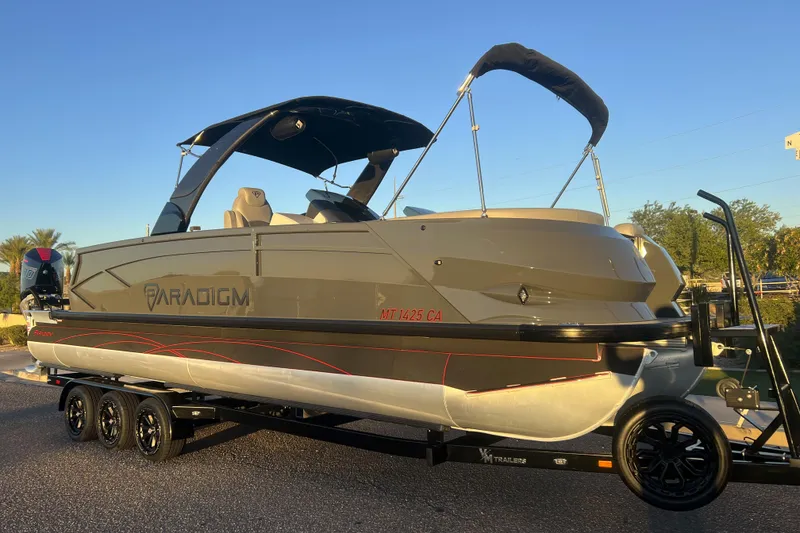 The Image of 2025 Paradigm 27SST pontoon boat on trailer, sleek design, sunny day. - 0