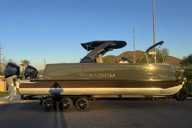 Slide: The Image of 2025 Paradigm 27SST pontoon boat with dual 300 horsepower engines on a trailer. - 2