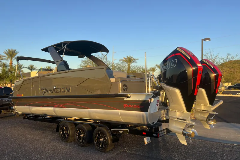 Slide: The Image of 2025 Paradigm 27SST pontoon boat with dual engines on a trailer, sunny day. - 3
