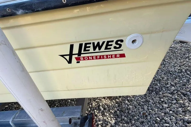 Slide: The Image of 1972 Hewes 17 Bonefisher boat side view with logo, on gravel surface. - 10