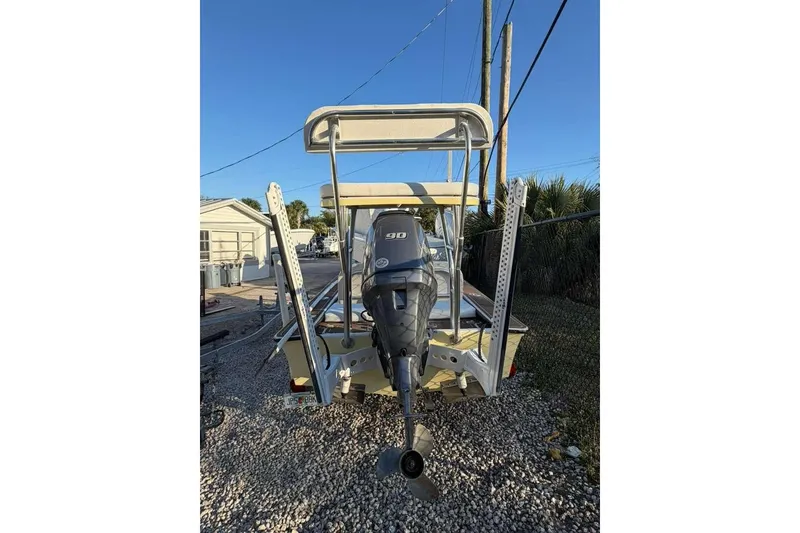 Slide: The Image of 1972 Hewes 17 Bonefisher boat with outboard motor, parked on gravel. - 2