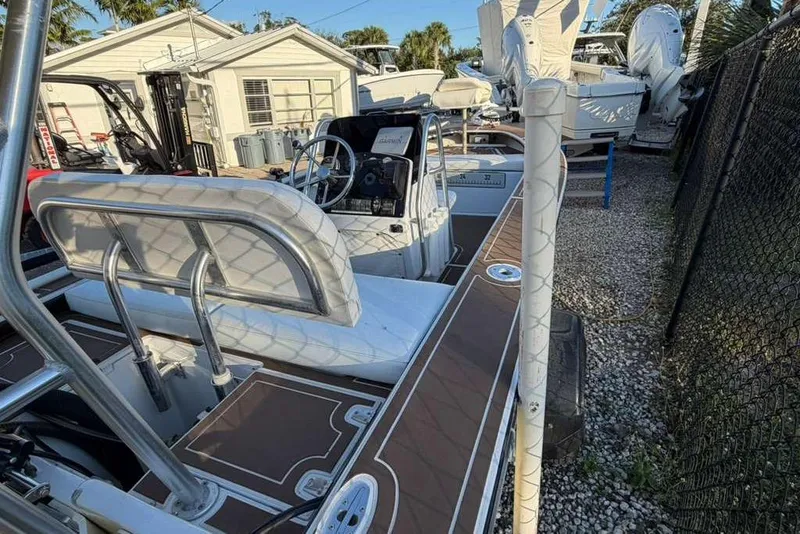 Slide: The Image of 1972 Hewes 17 Bonefisher boat with seating and steering wheel, parked near a fence. - 7