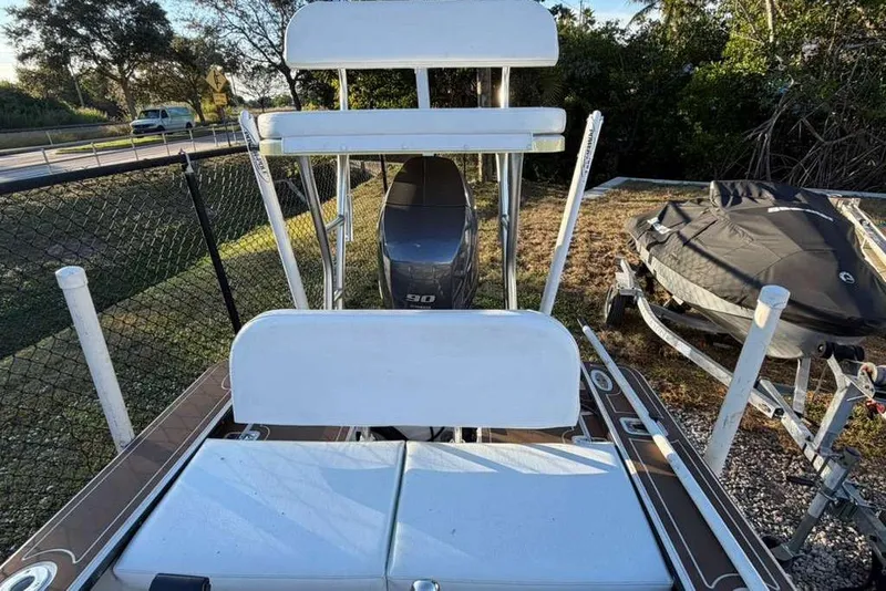 Slide: The Image of 1972 Hewes 17 Bonefisher boat with seating and outboard motor, parked near a fence. - 4