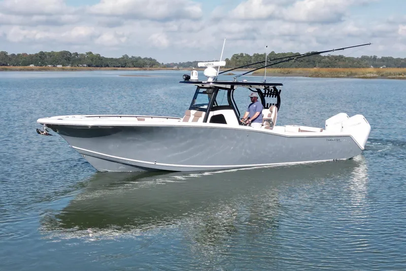 The Image of 2025 Tidewater 320 CC Adventure boat cruising on calm water under a partly cloudy sky. - 0
