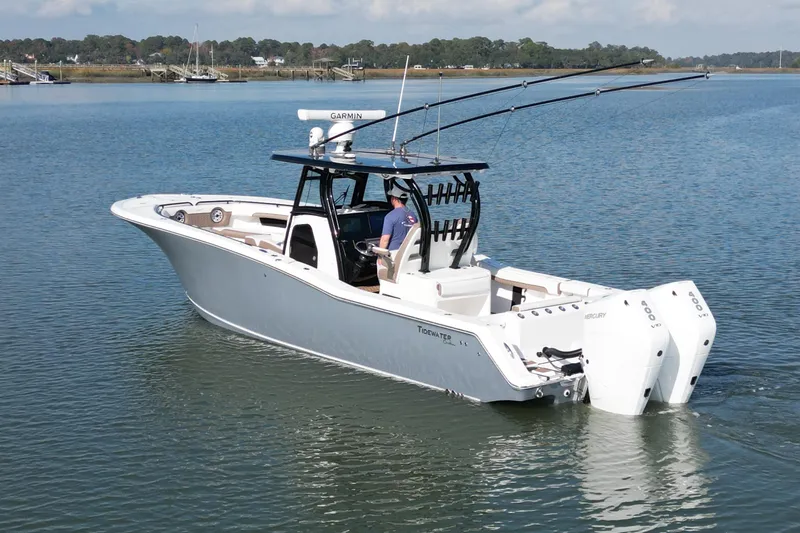 Slide: The Image of 2025 Tidewater 320 CC Adventure boat with dual engines on calm water. - 2