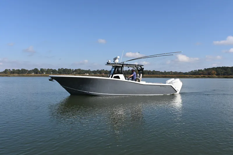 Slide: The Image of 2025 Tidewater 320 CC Adventure boat cruising on calm water under clear skies. - 3