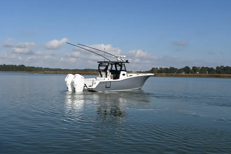 Slide: The Image of 2025 Tidewater 320 CC Adventure boat cruising on calm waters under a clear sky. - 7