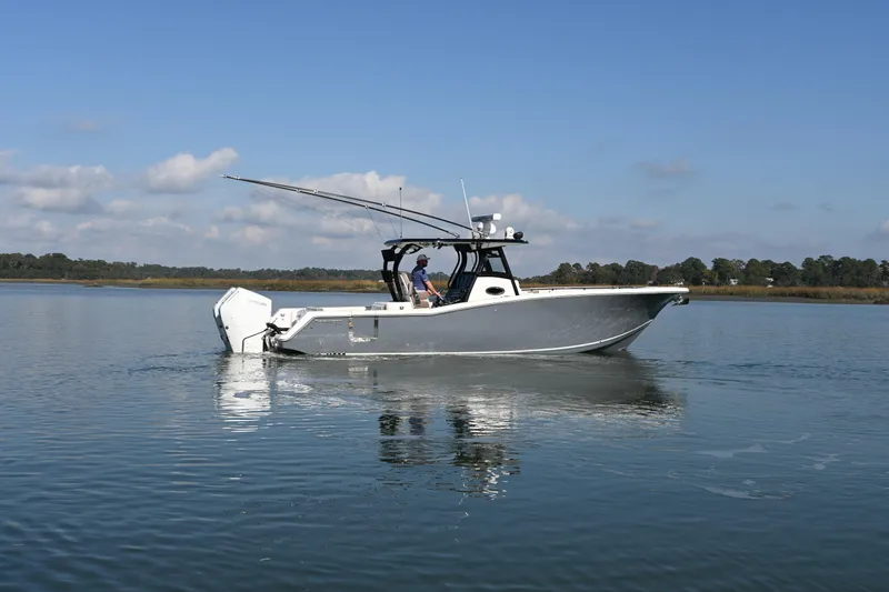 Slide: The Image of 2025 Tidewater 320 CC Adventure boat on calm water under blue sky. - 8