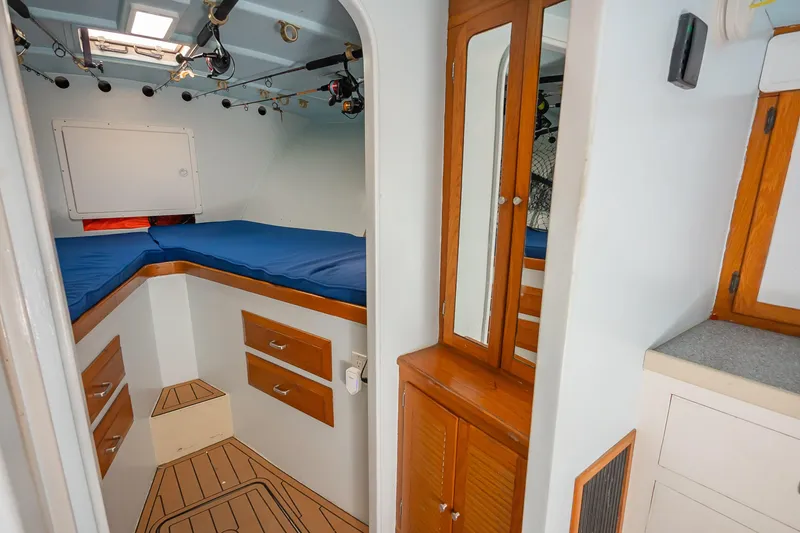 Slide: The Image of Interior of 1987 Custom Carolina Island Boatworks 34 Express, featuring cozy cabin with blue bedding. - 19