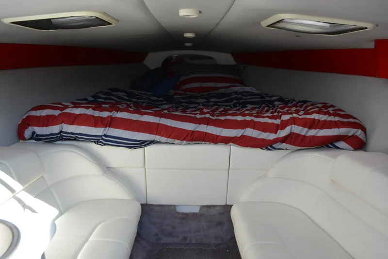 Slide: The Image of Interior cabin of 2000 Formula 271 FASTech boat with striped bedding and white seating. - 11
