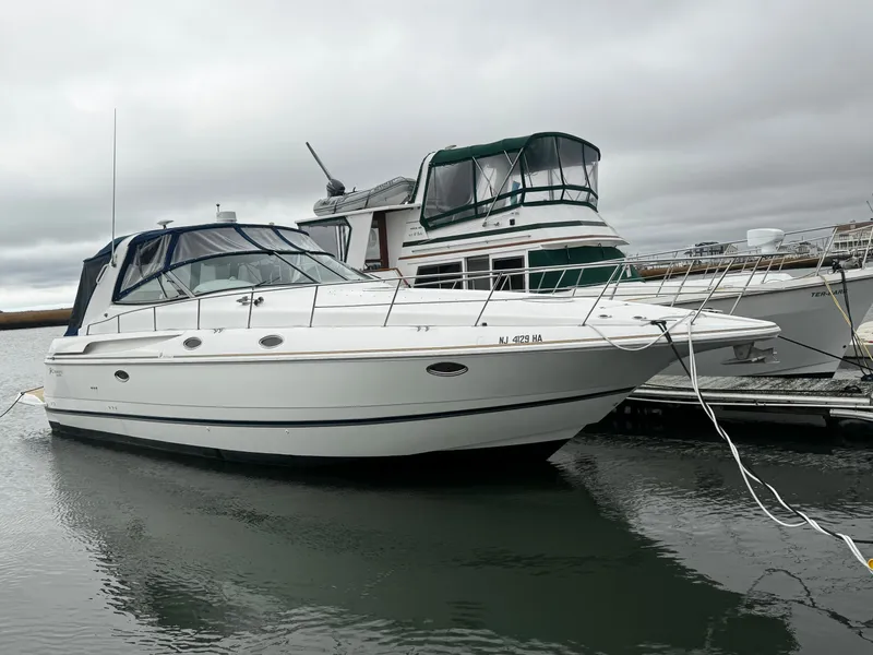 Slide: The Image of 1998 Cruisers Yachts 3870 Esprit docked in a marina under cloudy skies. - 3