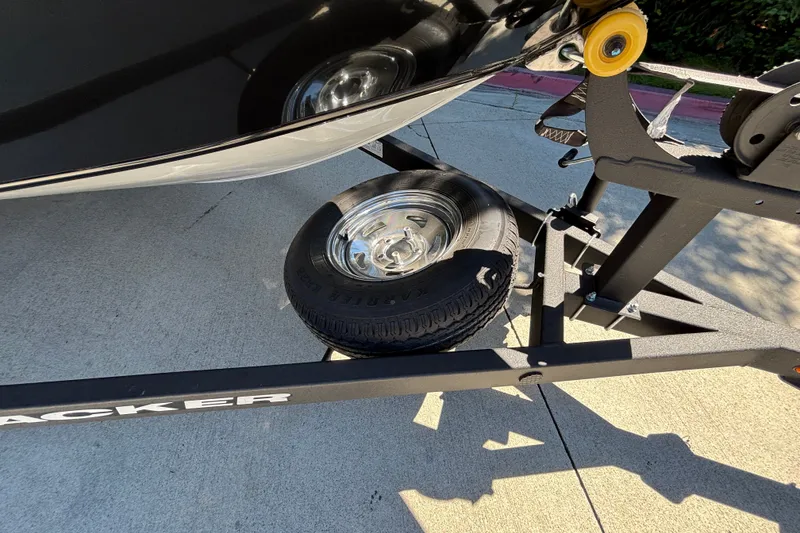 Slide: The Image of 2026 Tracker Pro Guide V-175 WT boat trailer with spare tire on pavement. - 13