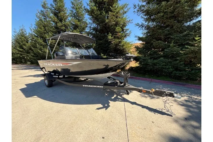 Slide: The Image of 2026 Tracker Pro Guide V-175 WT boat on trailer, parked outdoors near trees. - 14