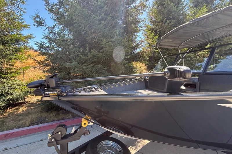 Slide: The Image of 2026 Tracker Pro Guide V-175 WT boat with Minn Kota trolling motor in a wooded area. - 33