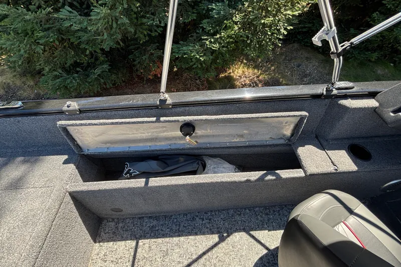 Slide: The Image of 2026 Tracker Pro Guide V-175 WT boat interior storage compartment with seat and greenery background. - 39