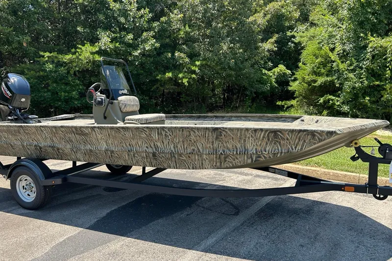 The Image of 2026 Tracker Grizzly 1860 CC boat on trailer, camo design, parked outdoors. - 0