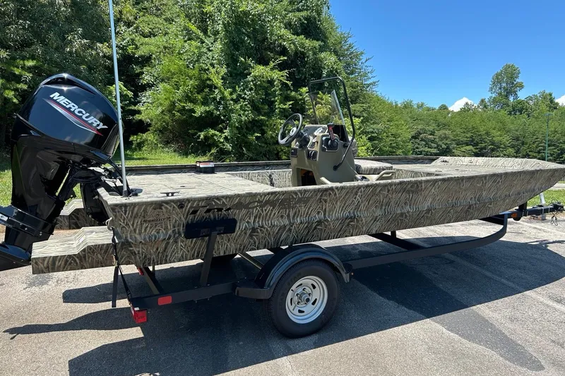 Slide: The Image of 2026 Tracker Grizzly 1860 CC boat with Mercury engine on trailer, surrounded by greenery. - 66