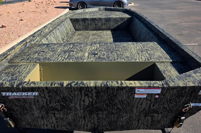 Slide: The Image of 2026 Tracker Grizzly 1648 Utility boat with camouflage design in a parking lot. - 2