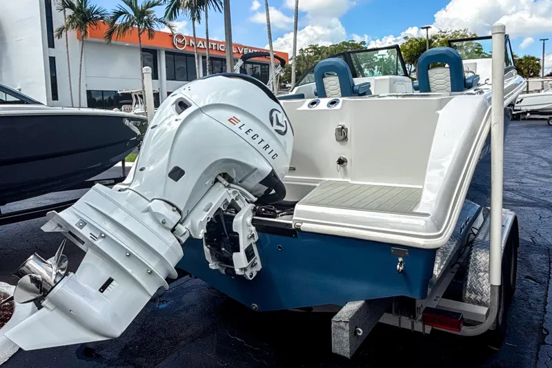 Slide: The Image of 2024 Aquasport AS DC 22 boat with electric motor, displayed outdoors at a dealership. - 2