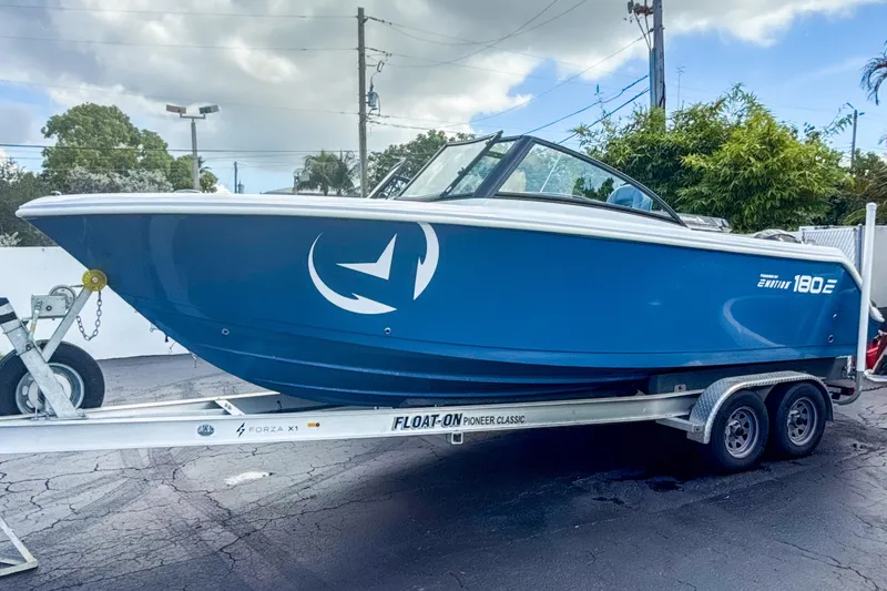 Slide: The Image of 2024 Aquasport AS DC 22 boat on trailer, blue hull, parked outdoors. - 4