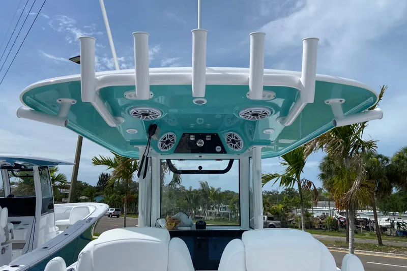 Slide: The Image of 2026 Sportsman Open 262 Center Console boat with rod holders and speakers, docked under a clear sky. - 23