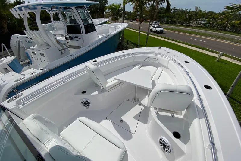 Slide: The Image of 2026 Sportsman Open 262 Center Console boat with white seating and table, parked near a road. - 44