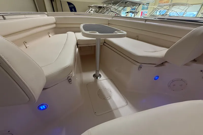 Slide: The Image of 2026 Grady-White Canyon 306 boat interior with seating and table, featuring ambient lighting. - 12