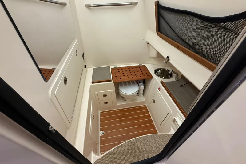 Slide: The Image of 2026 Grady-White Canyon 306 boat interior with compact bathroom and wooden flooring. - 14
