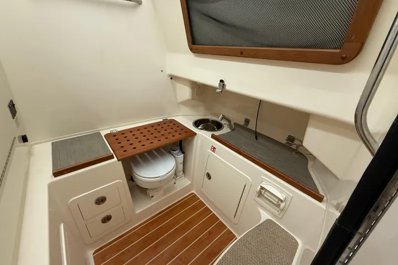 Slide: The Image of 2026 Grady-White Canyon 306 boat interior with compact bathroom and wooden accents. - 15