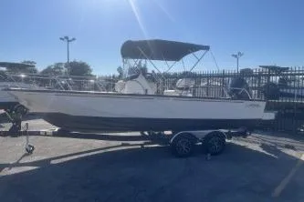 Slide: The Image of 2024 Boston Whaler 210 Montauk boat on trailer, parked outdoors under clear sky. - 2