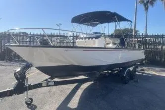 Slide: The Image of 2024 Boston Whaler 210 Montauk boat on trailer, parked outdoors under clear sky. - 3